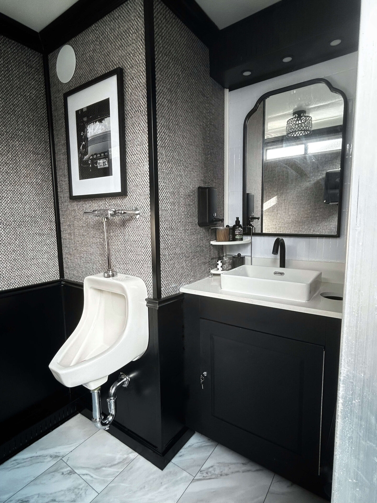 Urinal and sink area inside men's side of luxury restroom trailer