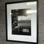 Black and white Porsche wall art inside the men's washroom of a Toiluxe luxury mobile restroom trailer for upscale outdoor events.