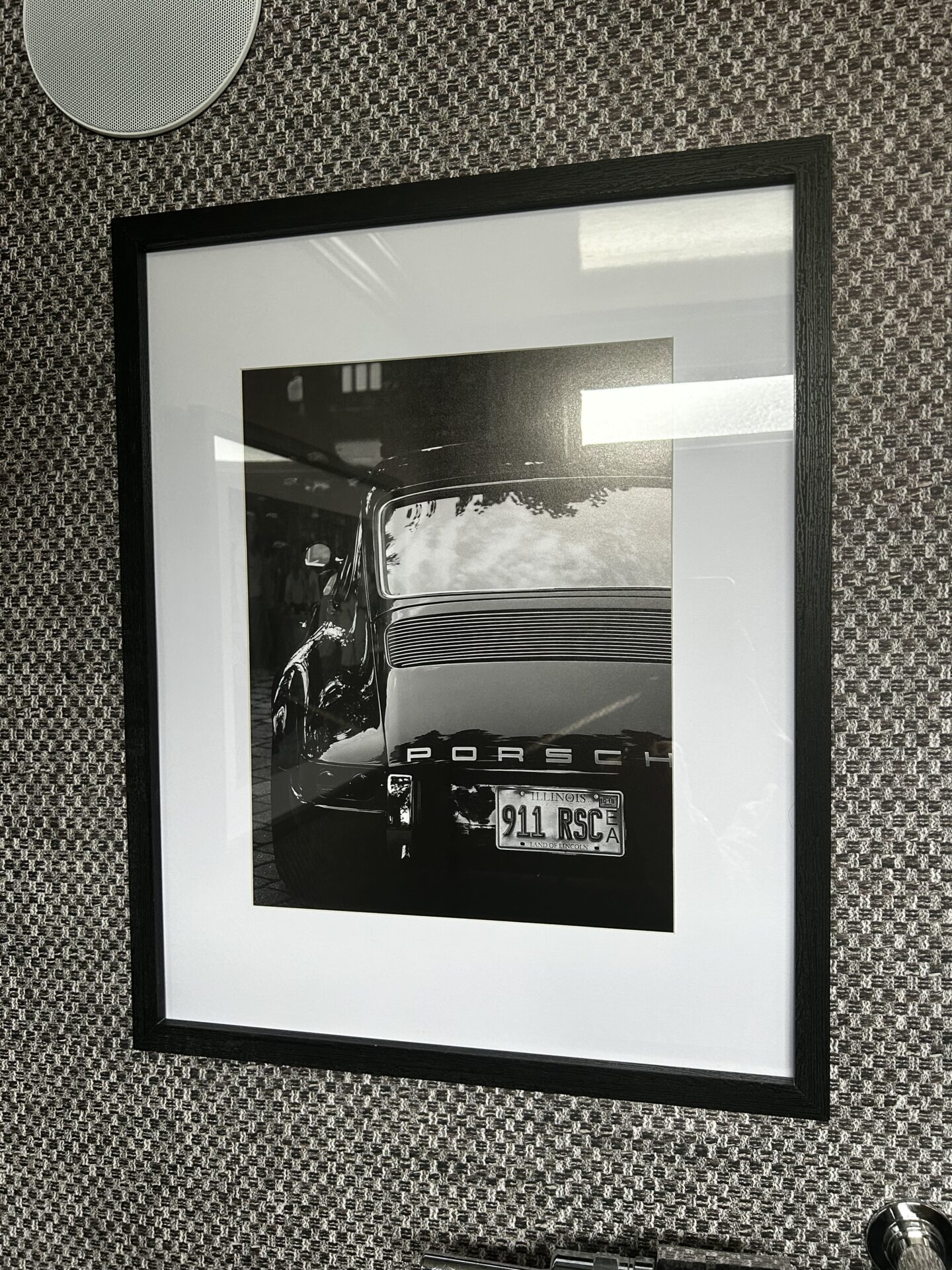 Black and white Porsche wall art inside the men's washroom of a Toiluxe luxury mobile restroom trailer for upscale outdoor events.