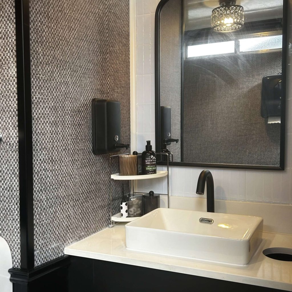 Dark vanity and mirror design inside a luxury restroom trailer bathroom